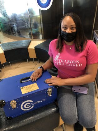 Janelle Blouin sits next to a CuddleCot device she donated to Denver Health. This device used by bereaved parents after the loss of a baby.